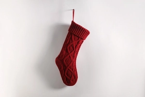 Close-up of red cable knit Christmas stocking with diamond patterns and hanging loop