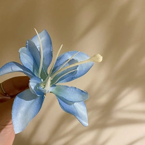 Detailed macro view of a sky blue fabric hibiscus hair clip with realistic petal texture