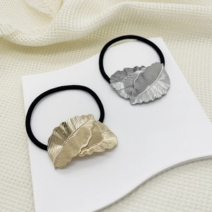 Detailed view of black elastic hair ties featuring polished gold and silver metal feathers
