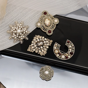 Detailed macro shot of vintage baroque brooches featuring pearls and sparkling rhinestones
