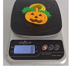 Weight measurement of a Halloween pumpkin snap bracelet at approximately 8 grams