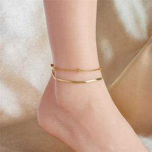 Close-up of double layer gold-plated stainless steel anklet with beads on satin fabric