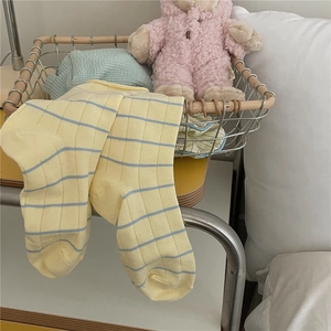 Close-up of soft yellow socks with blue stripes placed in a vintage bamboo basket