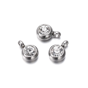 Detailed macro view of three silver stainless steel round pendants with clear zircon stones