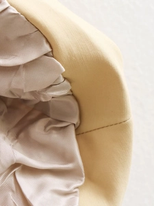 Detailaufnahme von beigem Baumwollstoff mit glattem champagnerfarbenem Satinfutter und Naht