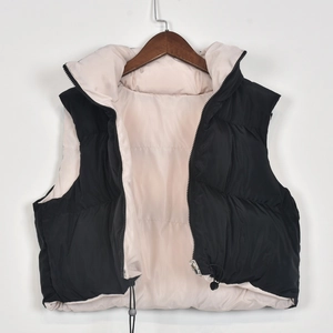 Detail of a padded vest with metal zipper, drawstring hem, and pink interior contrast