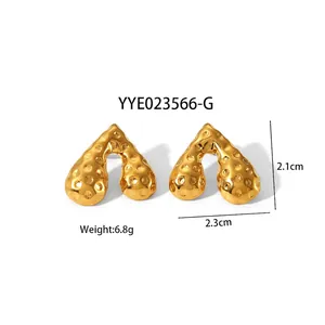 Détail des boucles d'oreilles dorées en acier inoxydable avec texture pointillée et taille