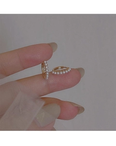 Macro view of dainty gold pearl huggie earrings with small white beads on a metal frame