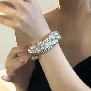 Close-up of a silver-toned wide woven texture metal cuff bracelet on a female wrist