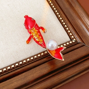 Macro shot of koi fish brooch with red and yellow enamel, pearl detail on gold alloy