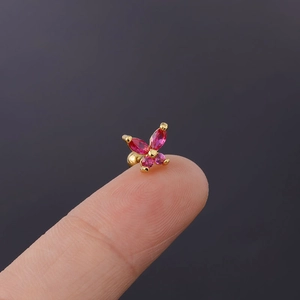 Macro shot of tiny butterfly stud earring with pink zircon stones held on a fingertip