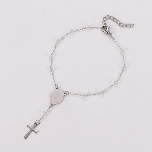 Macro shot of silver metal chain bracelet with Virgin Mary medal and cross pendant