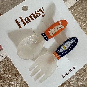 Detail of cute cat and fish cartoon hair clips on a spoon and fork shaped resin set