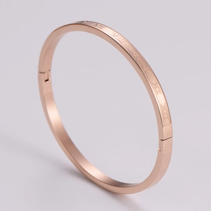 Detailed view of rose gold hinged bangle with Roman numeral engravings on stainless steel