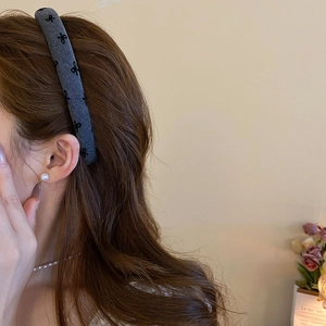 Close-up of elegant grey plush headband with black bow patterns on long wavy hair