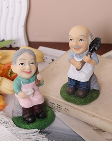 Dettaglio delle figurine di coppia anziana in resina con dettagli vivaci e scena calda