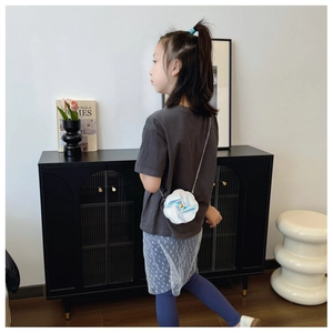 Dettaglio di una bambina con borsa a forma di fiore bianco cangiante e catena