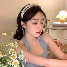 Detail of elegant pearl headband on female model in a cozy indoor setting
