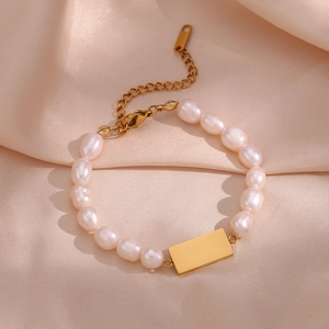 Detail of freshwater pearl bracelet with golden rectangle charm on pink silk fabric