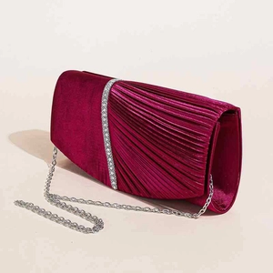 Dettaglio pochette da sera in velluto bordeaux a pieghe con bordo in strass e catena sottile