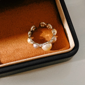 Macro detail of golden pearl ring with sparkling cubic zirconia on brown velvet box