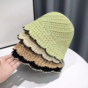 Detailed close-up showing four colors of hand-woven crochet straw bucket hats with wavy brims