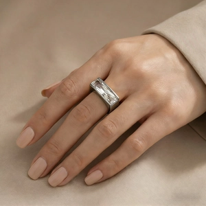 Close-up of a silver minimalist ring featuring a large rectangular crystal on a model hand