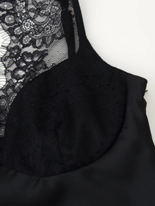 Close-up detail of black floral lace stitching and smooth satin fabric on a camisole