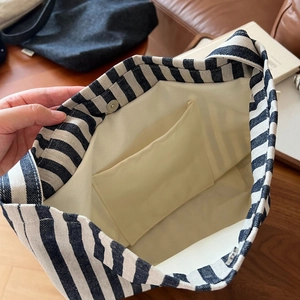 Detail of striped canvas tote bag showing interior lining, slip pocket and magnetic closure