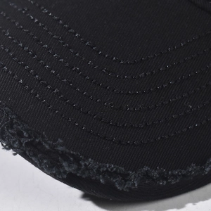 Close-up of distressed brim details on a black baseball cap with vintage frayed edges