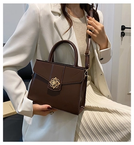 Détail d'un sac à main marron avec un fermoir doré décoratif en forme de fleur