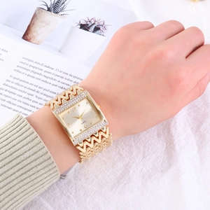 Close-up of golden square quartz watch with rhinestone bezel and unique M-shaped metal strap