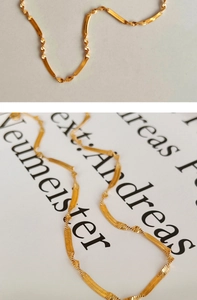 Detail shot of golden twisted snake chain necklace showing shiny metallic texture and curves