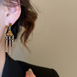 Detail of vintage golden triangle tassel earrings with amber gemstones on a model