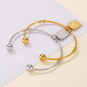 Detail shot of gold and silver open bangles with engraved square lucky charm pendants