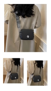 Close-up of black woven mini crossbody bag with wide geometric strap and metal lock