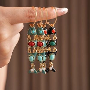 Detail of vintage enamel fish earrings featuring colorful gemstones and retro design