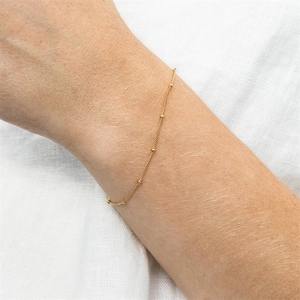 Minimalist gold-plated stainless steel layered bead chain bracelet on a woman's wrist