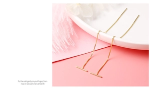 Detailed view of elegant gold tassel ear threads with a bar charm on a decorative plate