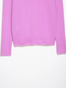 Detailed macro view of the ribbed hem and cuffs on this soft pink knitted sweater