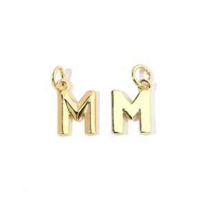 Close-up of shiny 18K gold letter M pendant charms with cubic zirconia stones