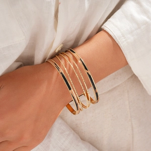 Dettaglio di bracciali dorati a strati con texture a spirale e motivi leopardati