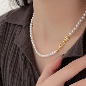 Detail of 925 silver necklace featuring small white pearls and a gold eye-shaped pendant