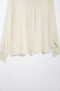 Detail of ruffled cuffs and delicate vertical stripes on a cream chiffon shirt