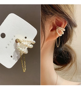 Detail of 14k gold chain ear cuff with white pearls and hanging tassel on a model
