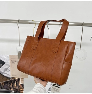 Detailed view of the minimalist brown PU leather tote bag with sturdy carry handles