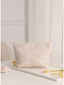 Beige tweed makeup bag with colorful speckles on white tray for skincare storage