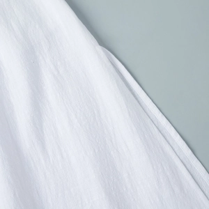 Close-up of high-quality white cotton fabric with detailed stitching and soft texture