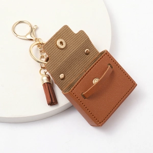 Nahaufnahme der braunen Mini-Ledertasche mit goldenem Schlüsselanhänger und Quaste