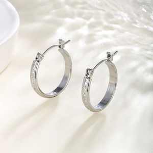 Macro shot of silver hoop earrings featuring intricate diagonal textured chain patterns
